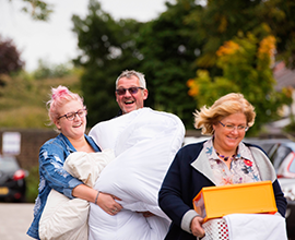student with her parents carrying duvet moving in